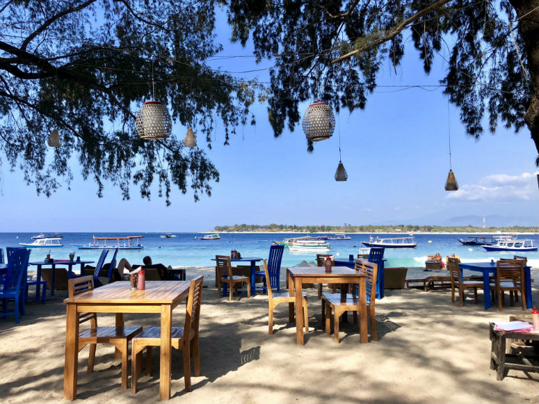 Tische und Stühle am Strand mit Sicht auf Meer