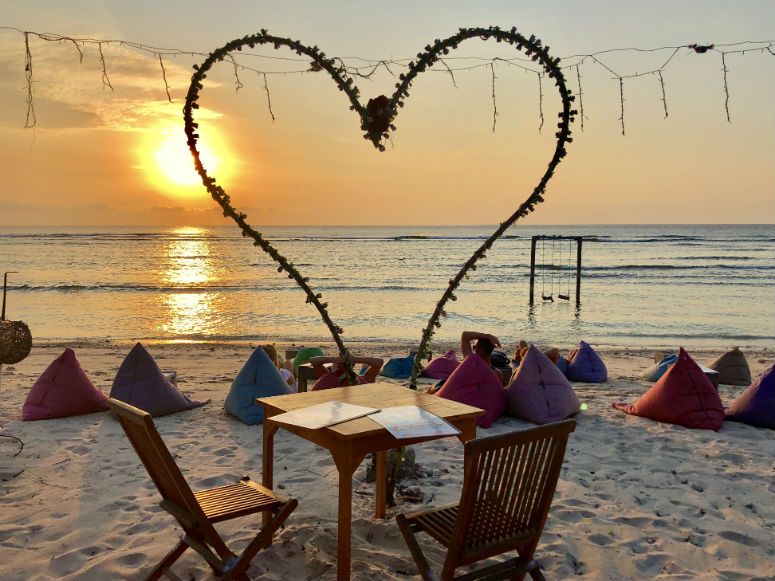 Tisch am Strand auf Gilitrawangan bei Sonnenuntergang mit großem Deko-Herz