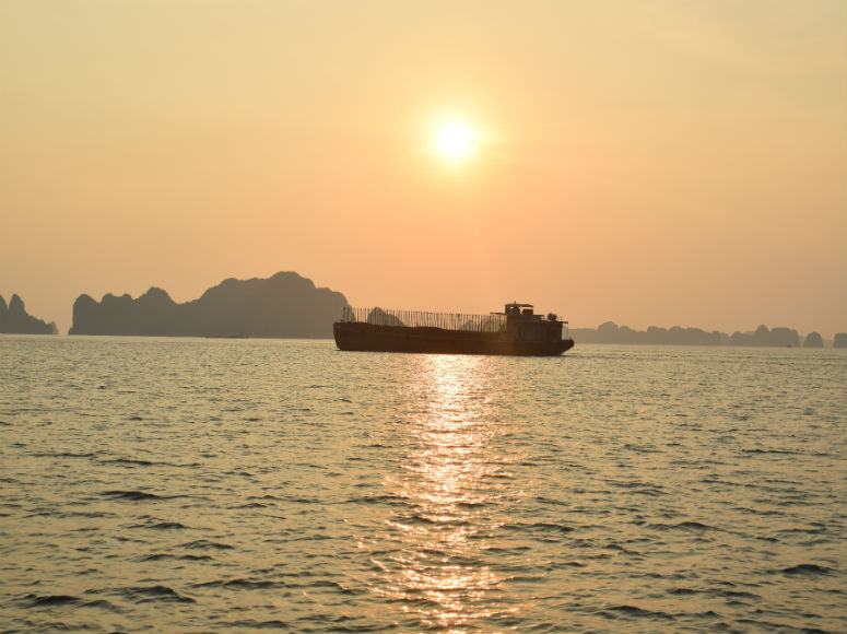 Meer Halong Bucht mit Schiff, Bergen und Sonne im Hintergrund