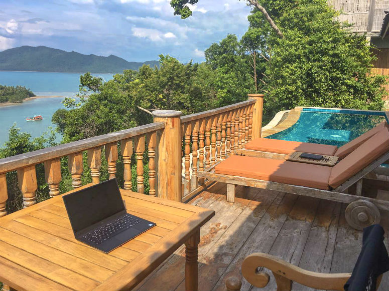 Reisen und arbeiten, Laptop auf Terrasse mit Blick auf Pool und Meer