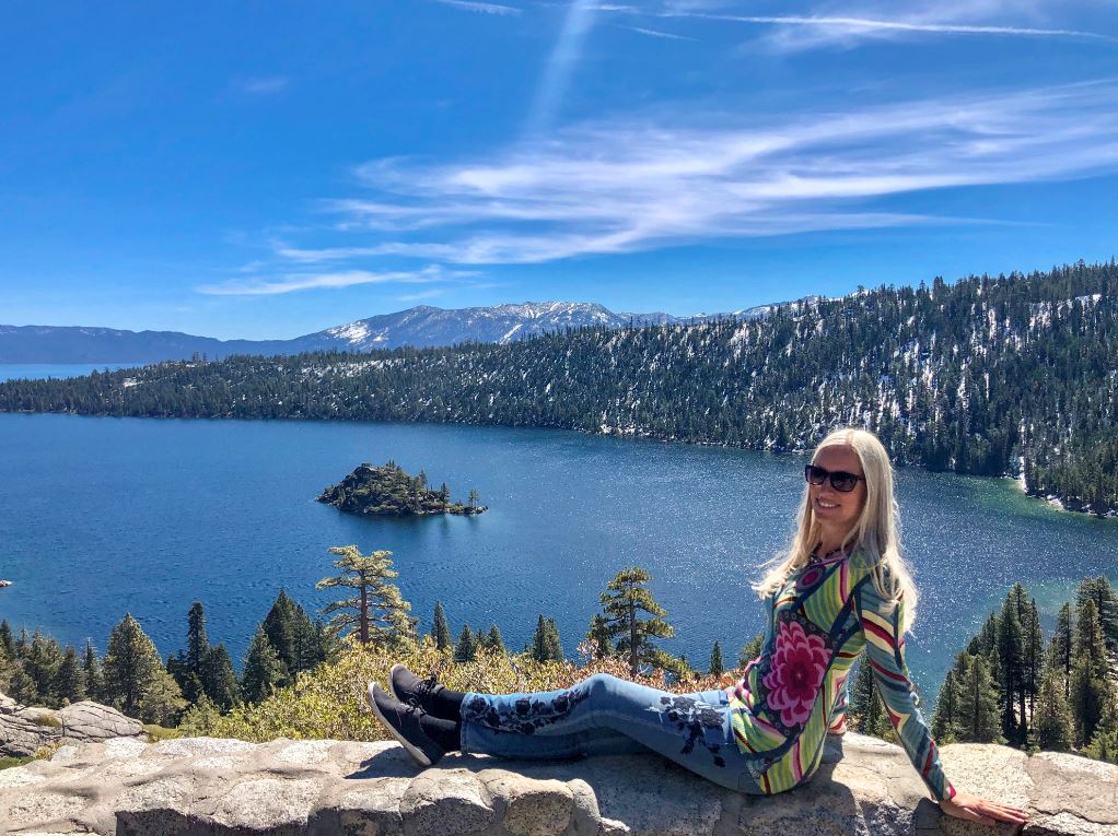 Frau sitzt auf Mauer, Emerald Bay im Hintergrund