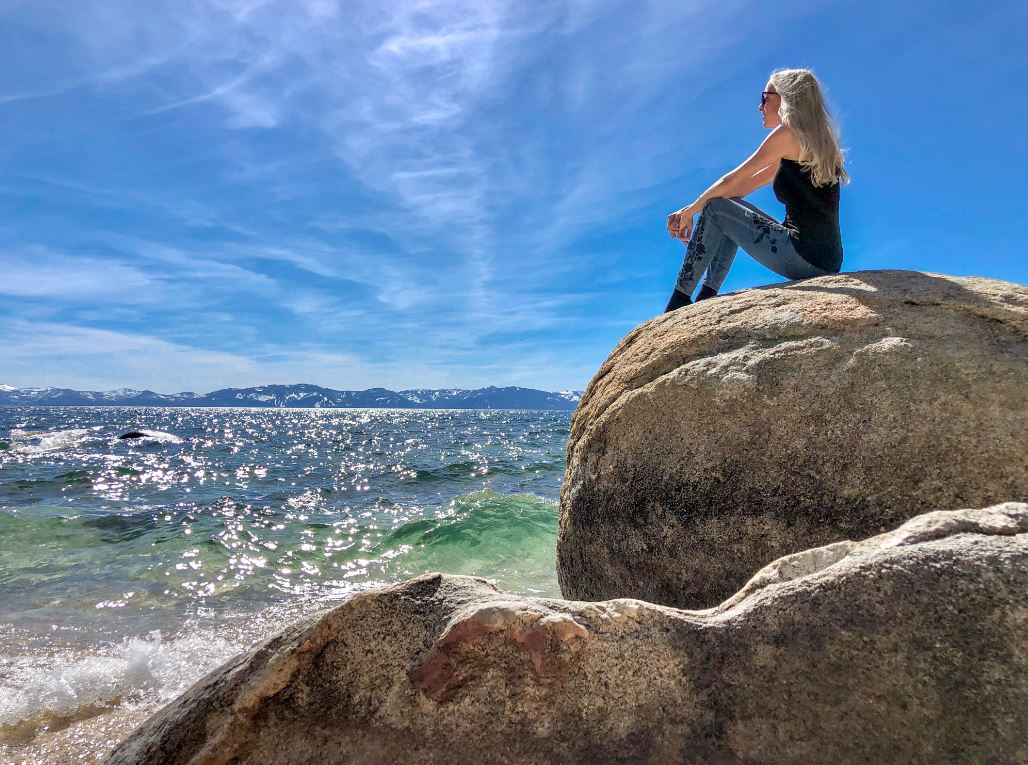 Wissenswertes über den Lake Tahoe, Frau sitzt auf Felsen am See