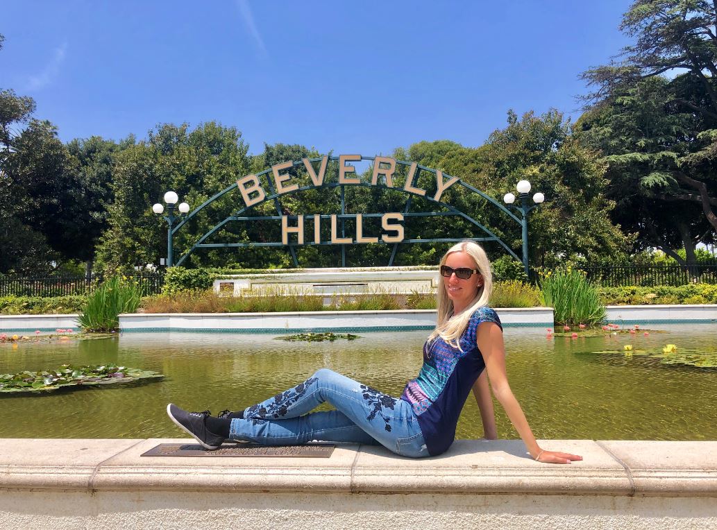 Los Angeles Sehenswürdigkeiten, Frau sitzt vor Beverly Hills Zeichen
