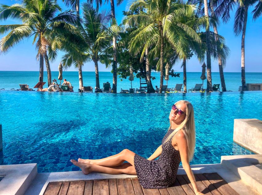 Koh Chang beste Reisezeit, Frau mit Kleid sitzt am Pool mit Blick auf Meer