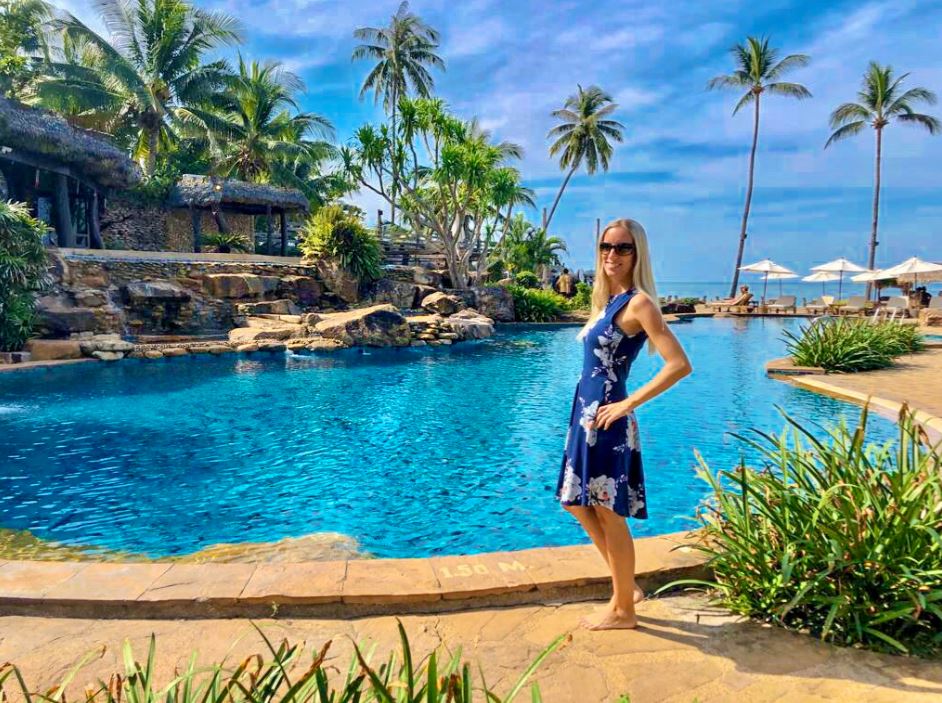 Frau im blauen Kleid steht vor Pool im Santhiya Tree Resort