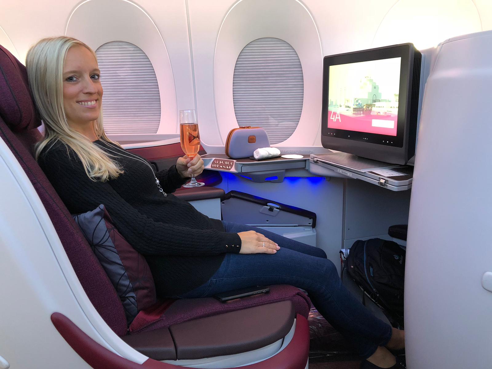 American Express Gold Card, Frau mit Sekt in der Hand sitzt in Business Class