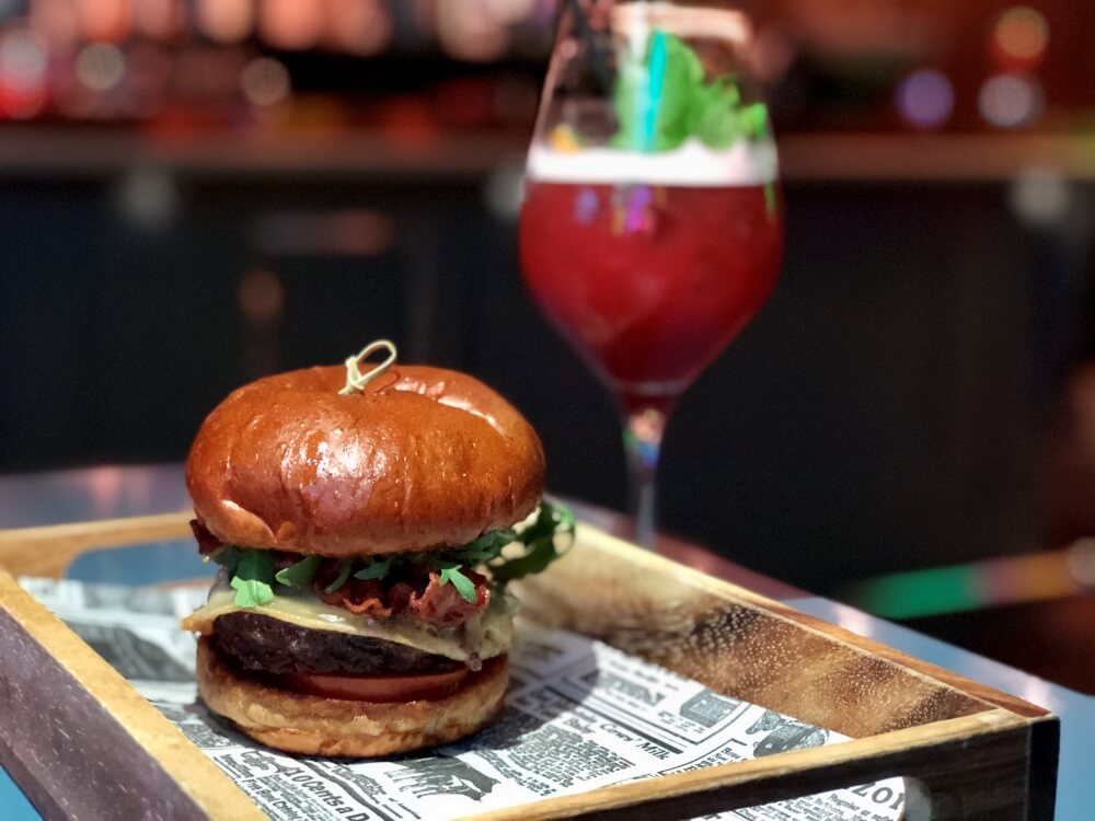 Burger auf Tablett mit Cocktail daneben