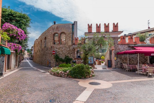 Blick auf alte Mauer in Bardolino am Gardasee hinter Restaurant mit roten Schirmen
