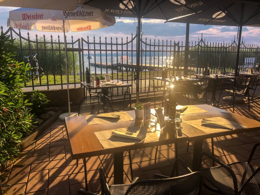 Blick auf Tisch in Restaurant mit See hinter Zaun in der Abendsonne