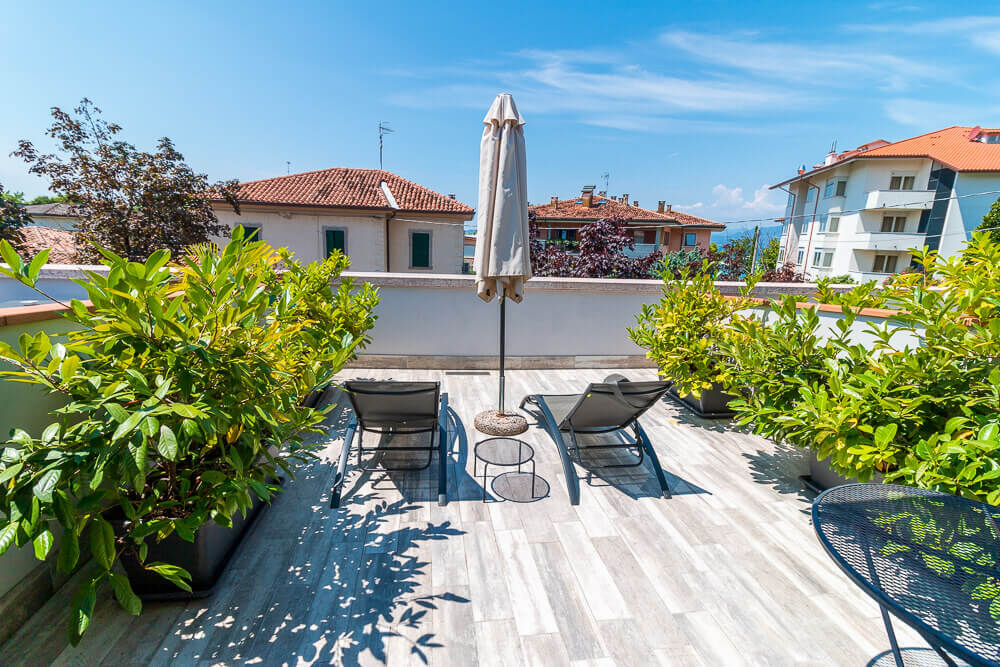 Blick auf Terrasse mit Liegen und Schirm vor Hotelzimmer