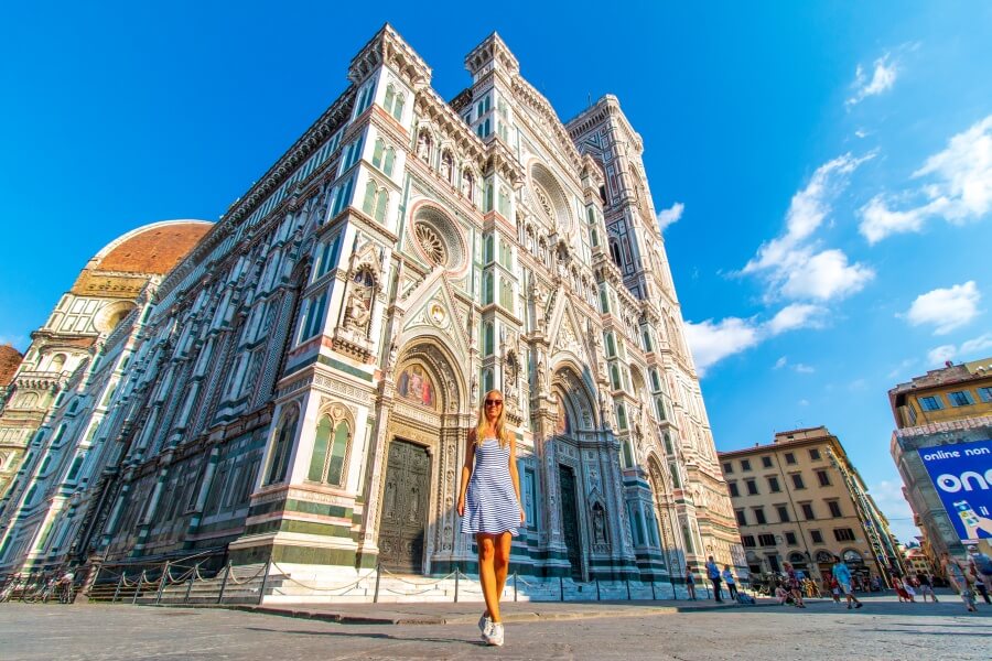 Frau im gestreiften kurzen Kleid steht vor Dom in Florenz