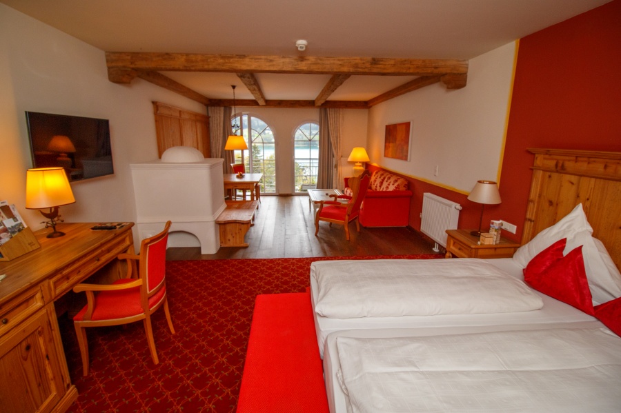 Blick auf Junior Suite im Ebners Waldhof mit Bett, Tisch, Kamin und Couch