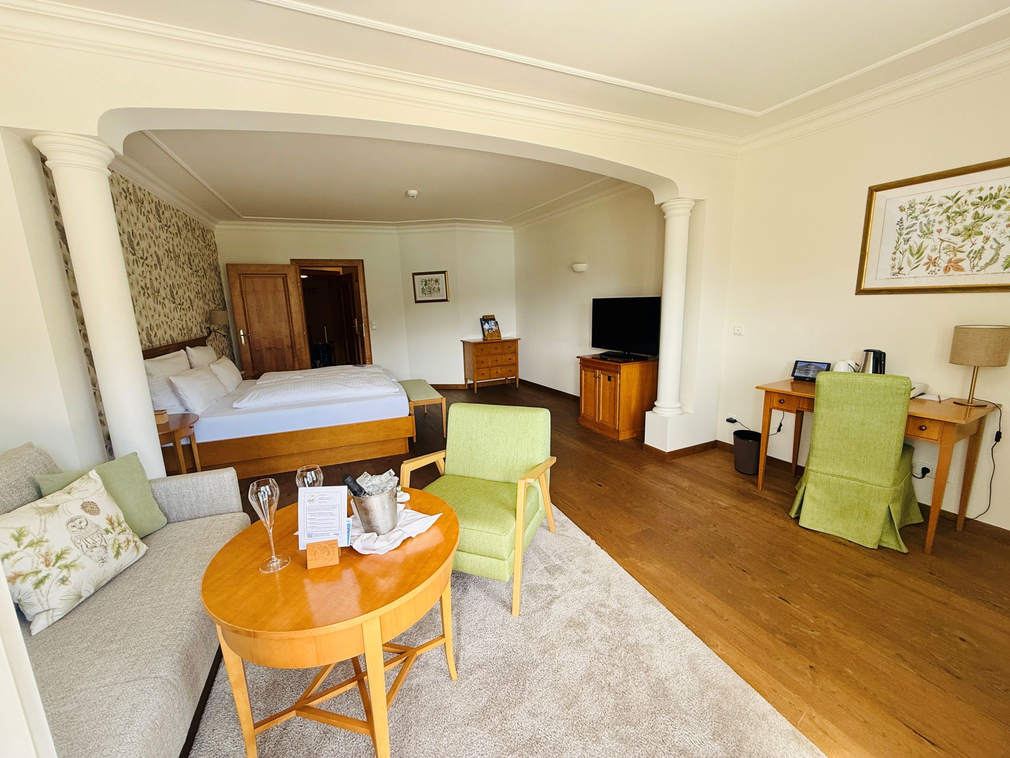 Blick auf Hotelzimmer mit Wohnbereich und Bett