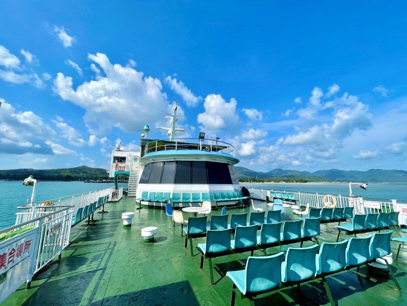 Außenbereich einer Fähre mit blauen Stühlen und grünem Boden, um damit nach Koh Phangan anzureisen