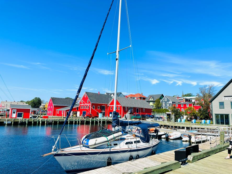 Weißes Segelboot am Hafen von Lunenburg vor schönen, roten Häusern bei blauem Himmel