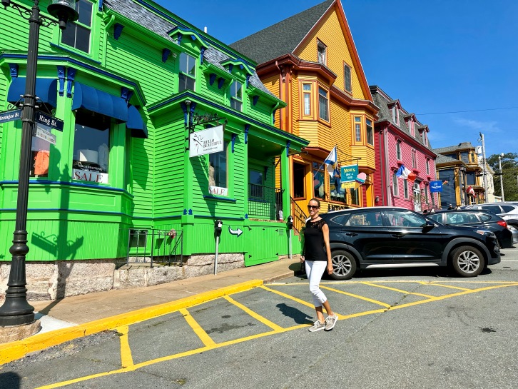 Frau steht vor bunten Häusern in Lunenburg Nova Scotia
