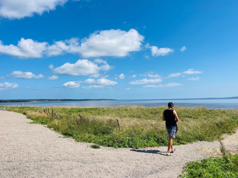 Mira Gut Beach Cape Breton, Mann läuft auf Weg zwischen hohem Gras zum Strand