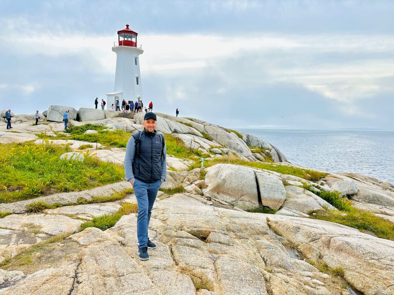 Mann steht auf Felsen vor Leuchtturm in Peggys Cove