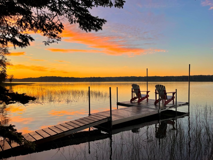 Sonnenaufgang am See, bunter Himmel, 2 Holzstühle auf kleinem Steg